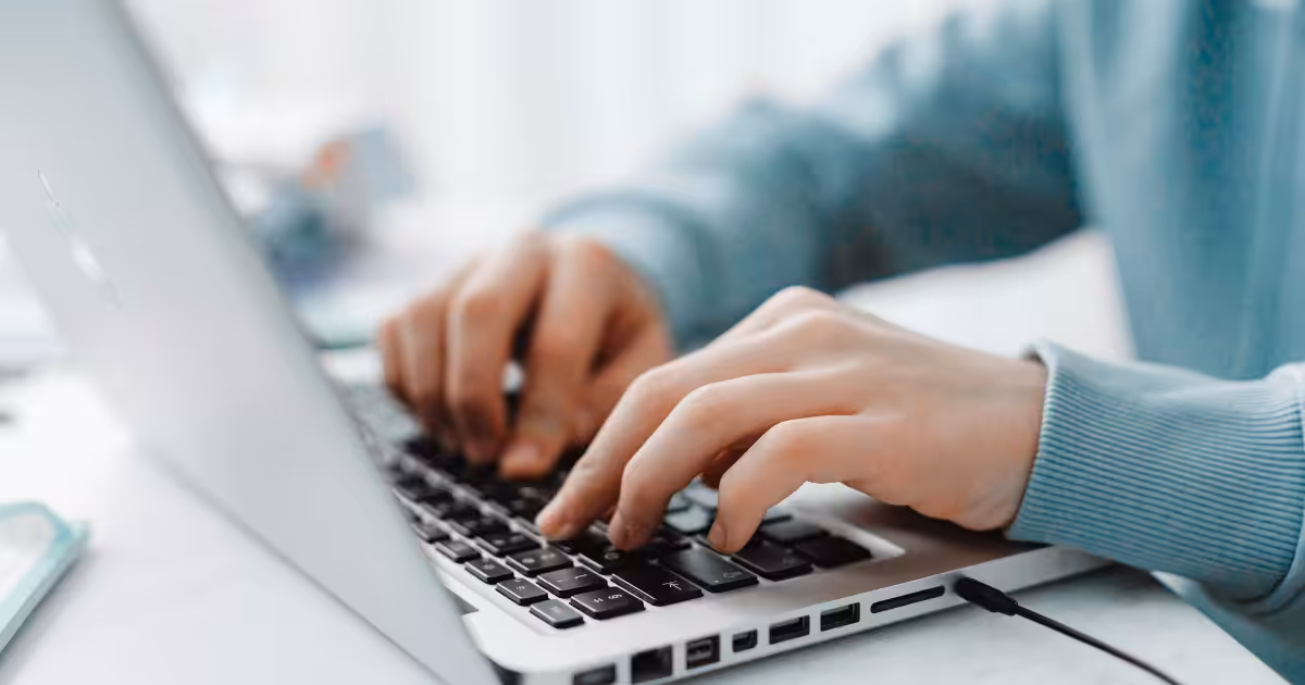 close up of a person's hands typing on an open keyboard