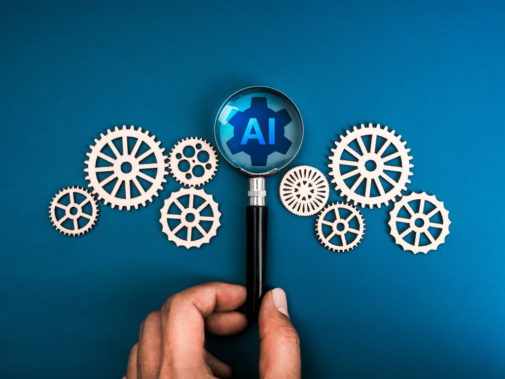 AI in magnifying glass surrounded by gears